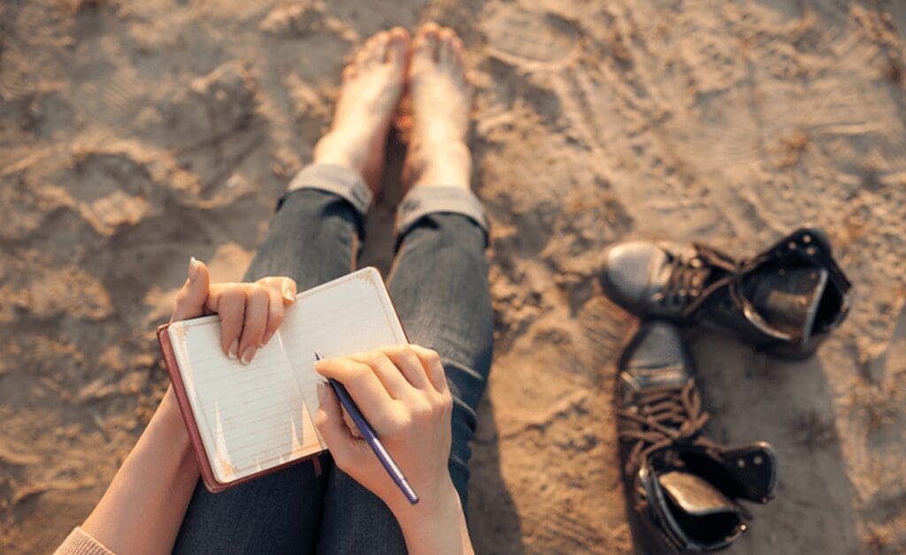 girl writing on beach